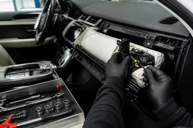 Mains expertes ajustant l'airbag passager, essentiel pour la fiabilité Range Rover Evoque.