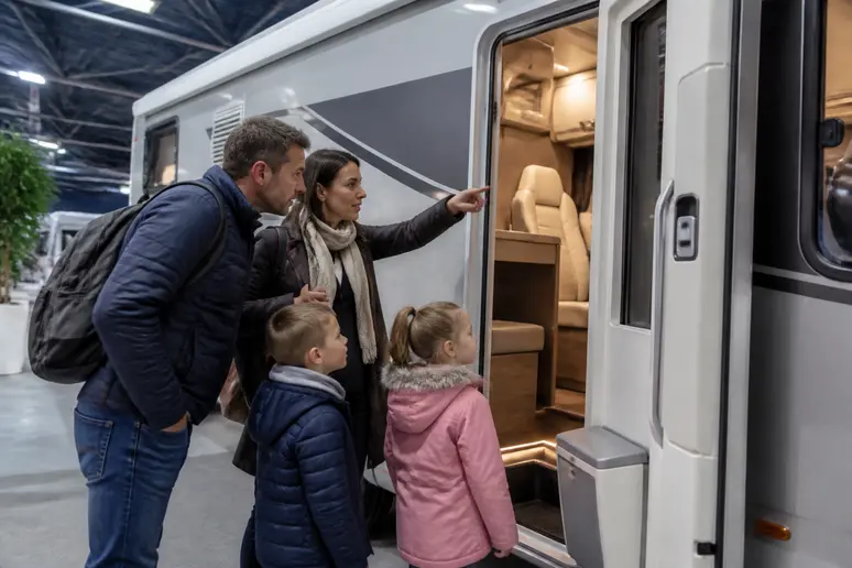 Un couple et leurs enfants découvrent un camping-car lors d'un salon spécialisé en 2026.