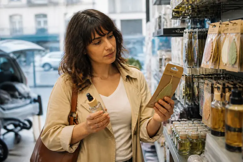 Une femme choisit un désodorisant pour sa voiture, cherchant un parfum agréable pour un habitacle qui sent bon.