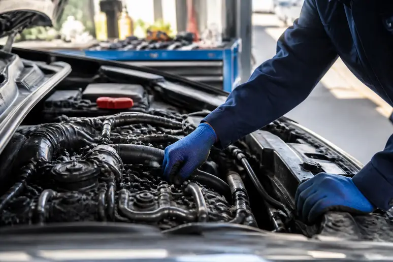 Un mécanicien examine un moteur de voiture pour identifier l'origine d'une odeur persistante, afin que la voiture sent bon.