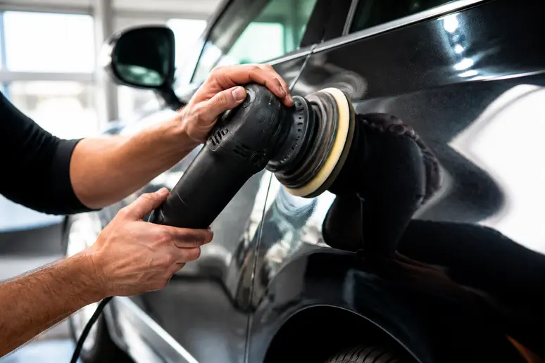 Technicien effectuant un polissage de carrosserie lors d'une étape de detailing auto