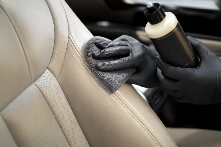 Application d'un soin nourrissant sur un siège auto en cuir avec un chiffon microfibre