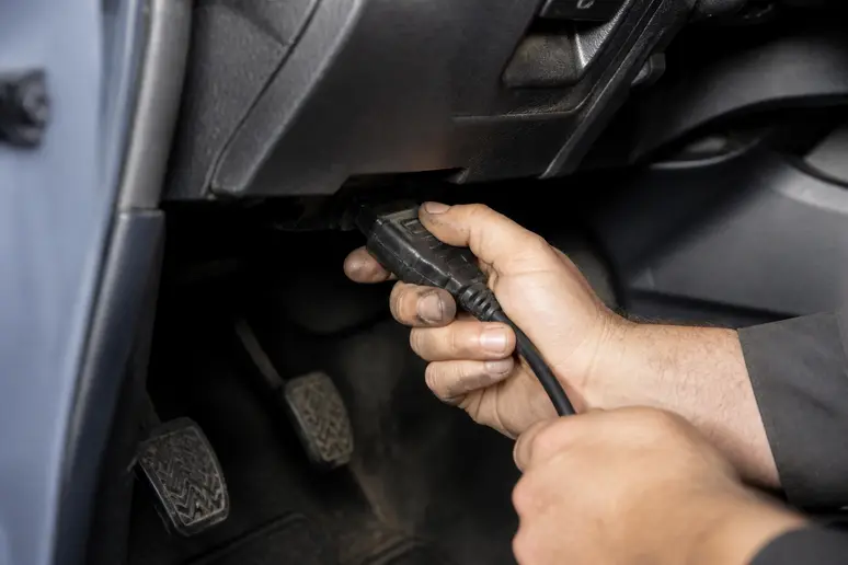 Connexion d'un outil de diagnostic sur la prise sous le tableau de bord d'une voiture