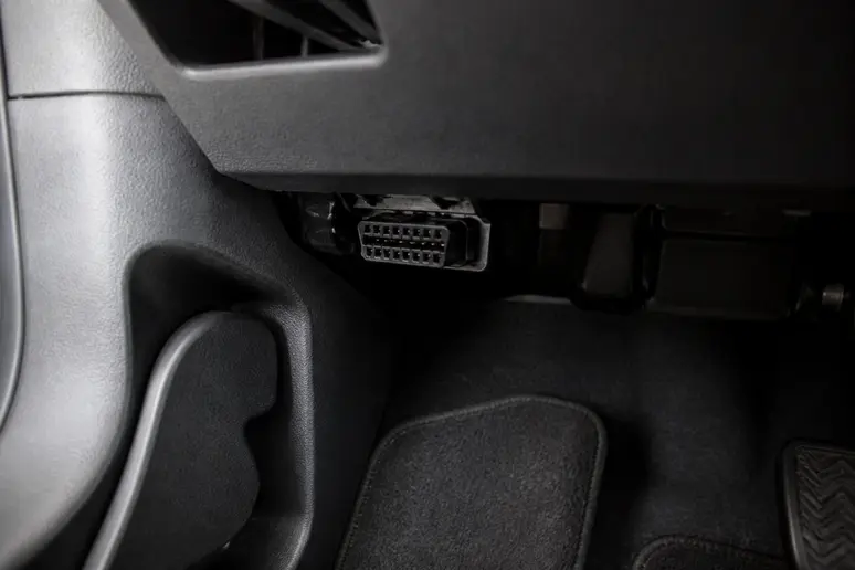 Prise diagnostic OBD visible sous le volant dans l'habitacle d'un véhicule