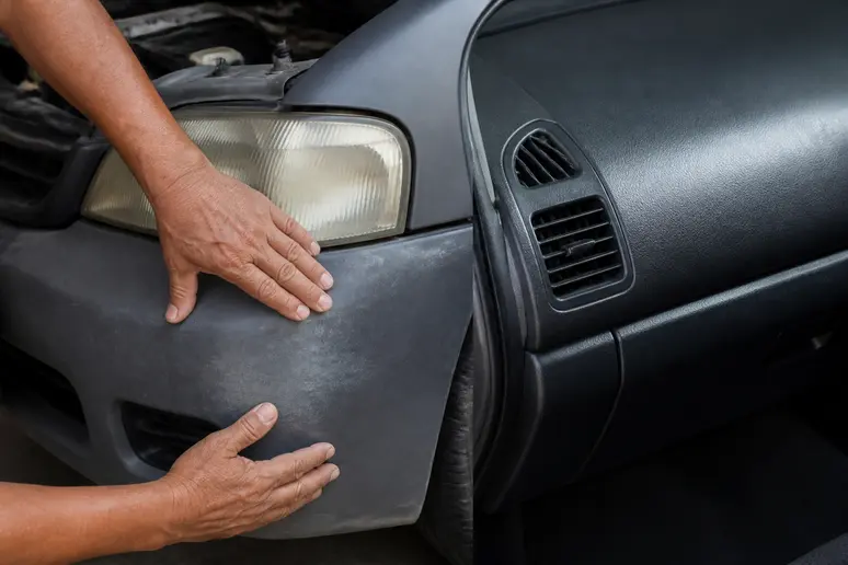 Inspection d'un pare-chocs de voiture grisé par les intempéries avant l'application d'un rénovateur plastique voiture