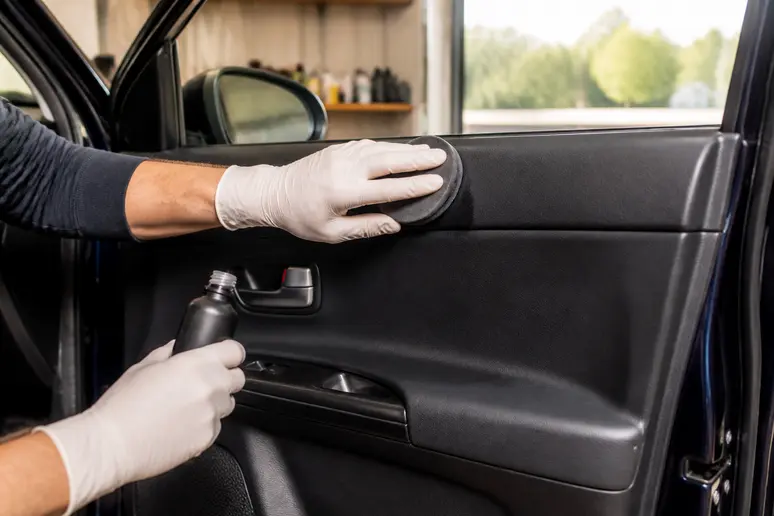 Application minutieuse d'un soin d'entretien sur le plastique de la console d'une voiture