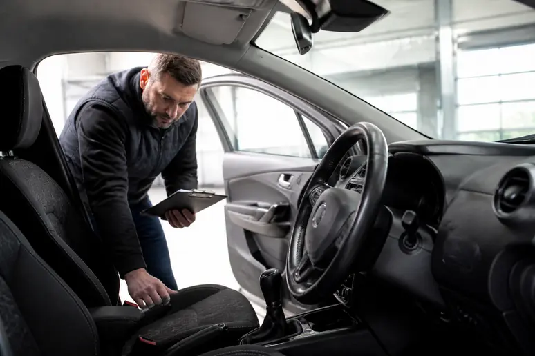Expert automobile évaluant l'habitacle d'un véhicule avant une offre de reprise.