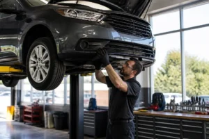 Un mécanicien inspecte le compartiment moteur d'une voiture dans un atelier pour identifier les 10-voitures-doccasion-a-eviter.