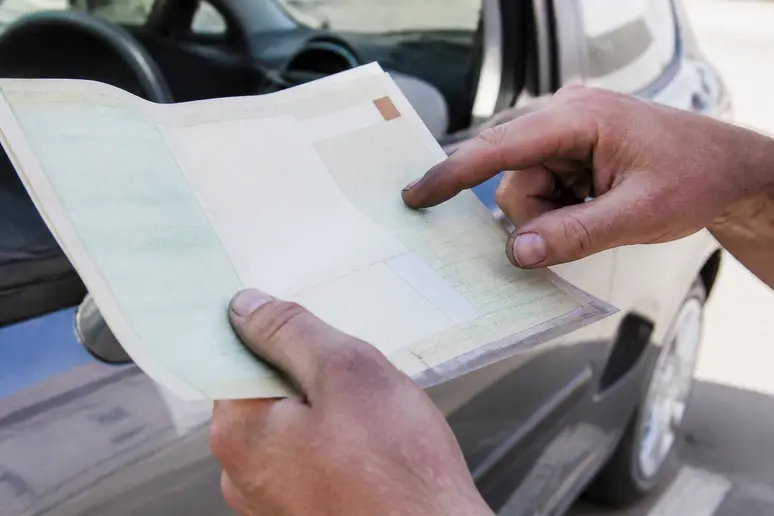 Mains d'un mécanicien pointant le numéro d'identification sur un certificat d'immatriculation.