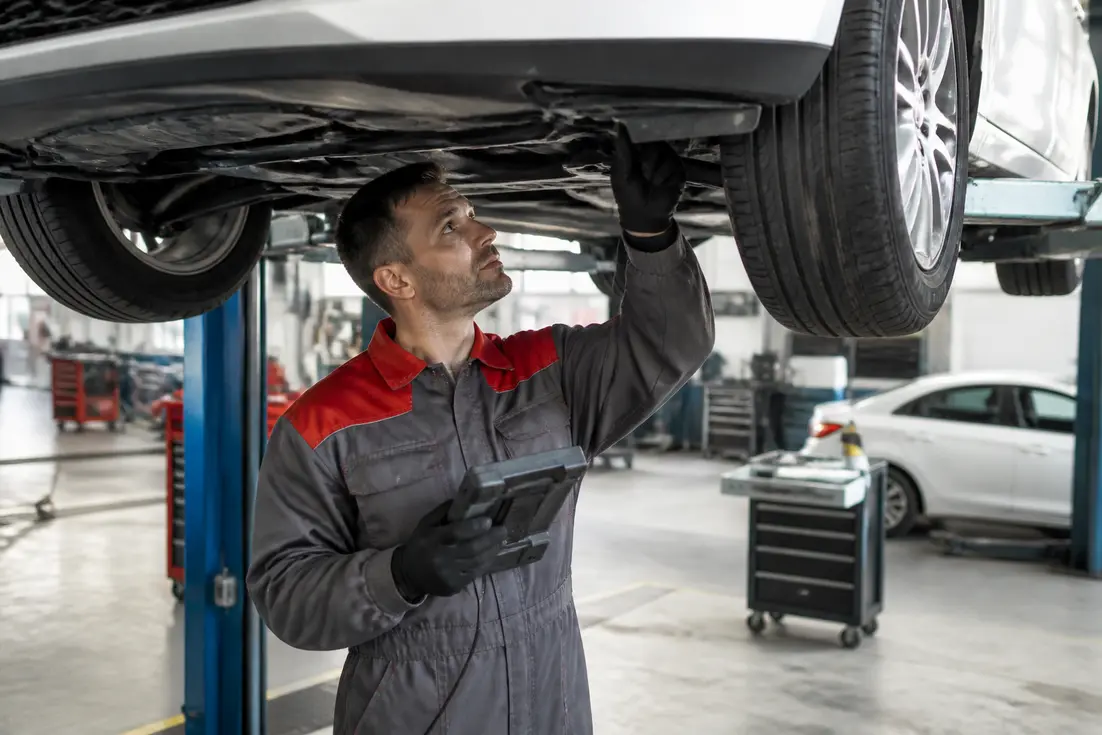 Mécanicien inspectant une voiture dans un atelier pour le controle-technique-annuel-vehicules-10-ans