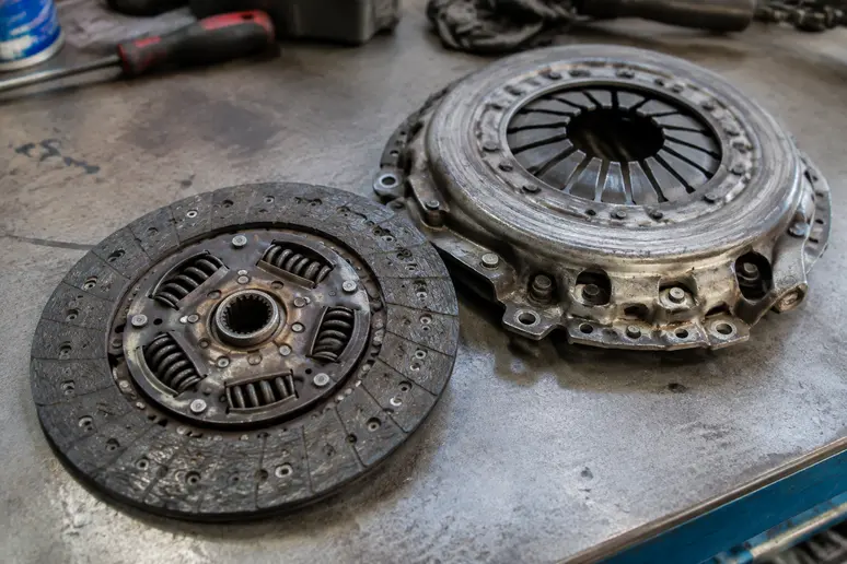Disque et mécanisme d'un embrayage usé posés sur un établi de garage.