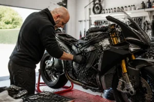 Mécanicien inspectant le moteur d'une superbike dans un atelier pour identifier la-plus-rapide-moto-du-monde.