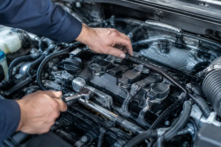 Mécano inspectant le compartiment moteur d'une voiture pour diagnostiquer des ratés d'allumage multiples