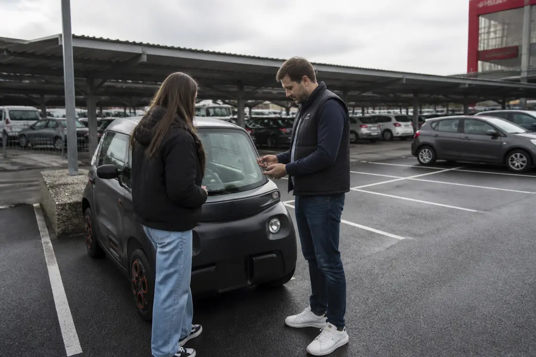 Un client consulte les conditions de prix-location-voiture-sans-permis-leclerc près d'un véhicule compact sur un parking