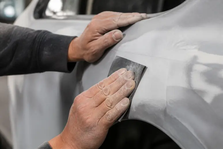 Ponçage minutieux d'un panneau de carrosserie automobile avant une peinture complète au black