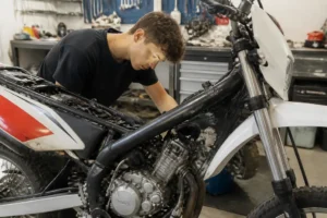 Un jeune mécanicien vérifie le moteur d'une moto rieju-mrx dans un atelier de réparation bien éclairé.