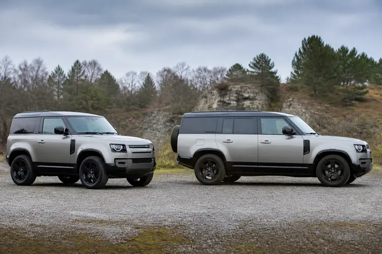 Deux Land Rover Defender à châssis court et long garés sur un chemin